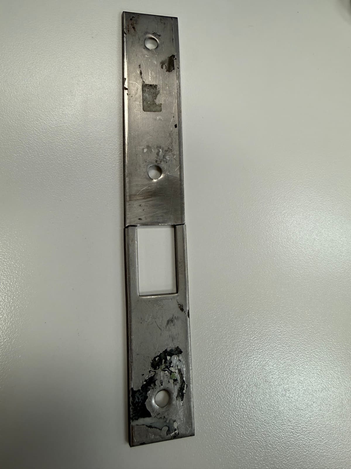 Close-up of the fractured latch bracket showing the break and worn mounting surface
