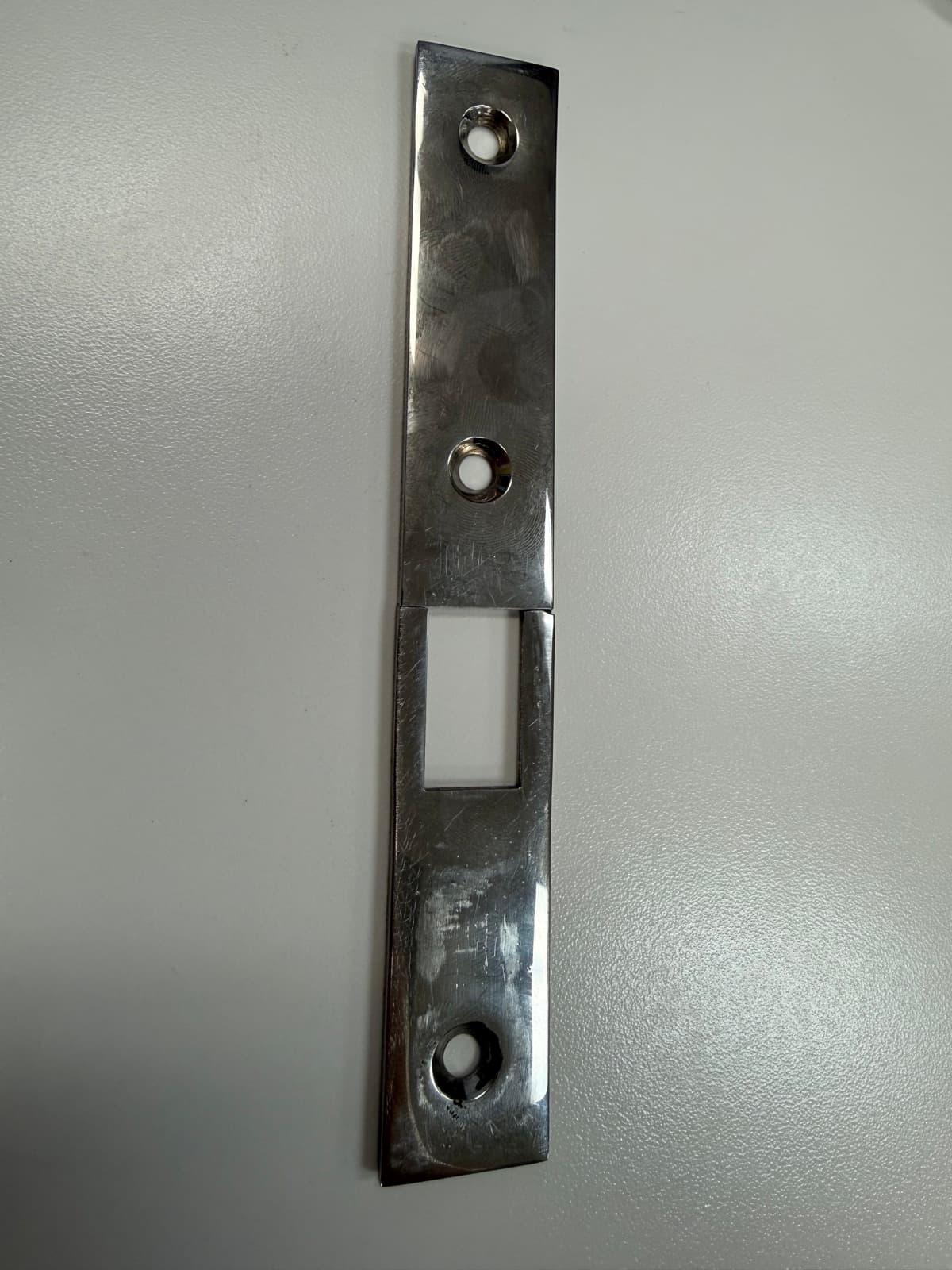 Original worn latch bracket showing surface damage and the fracture line