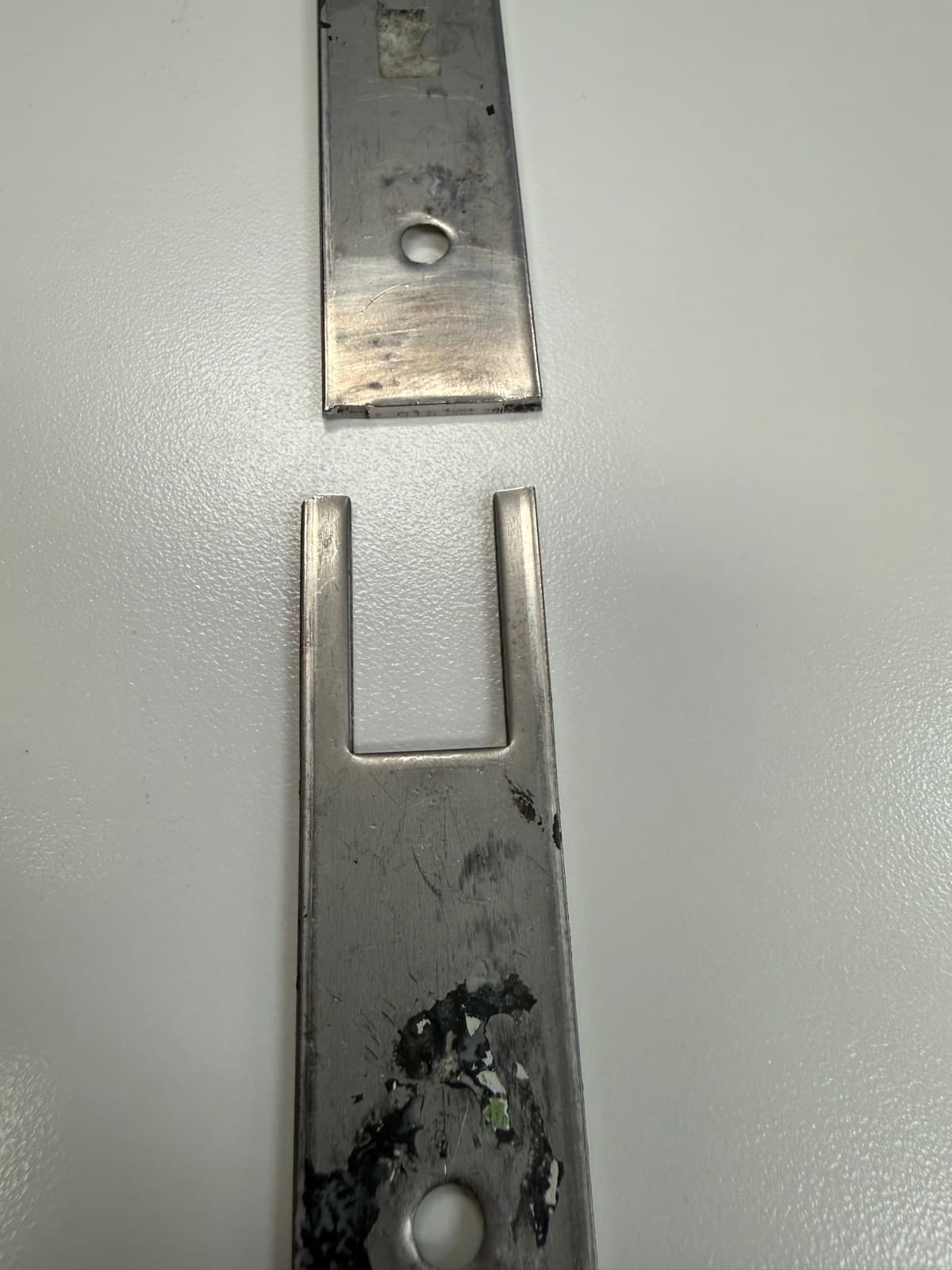Broken latch bracket separated into two pieces at the failure point