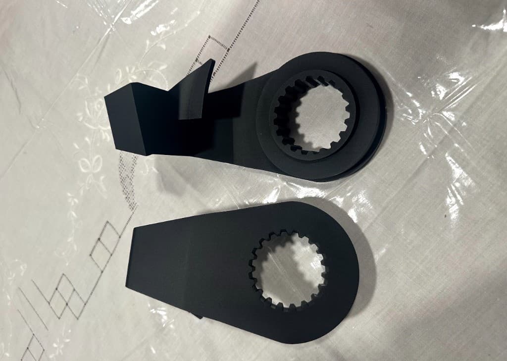 Two finished black windlass rope stops with splined hubs on a work surface