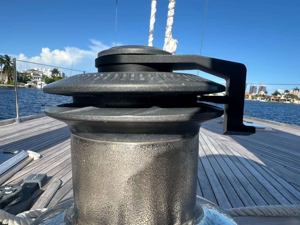 Sailboat winch on teak deck with waterfront homes in the background