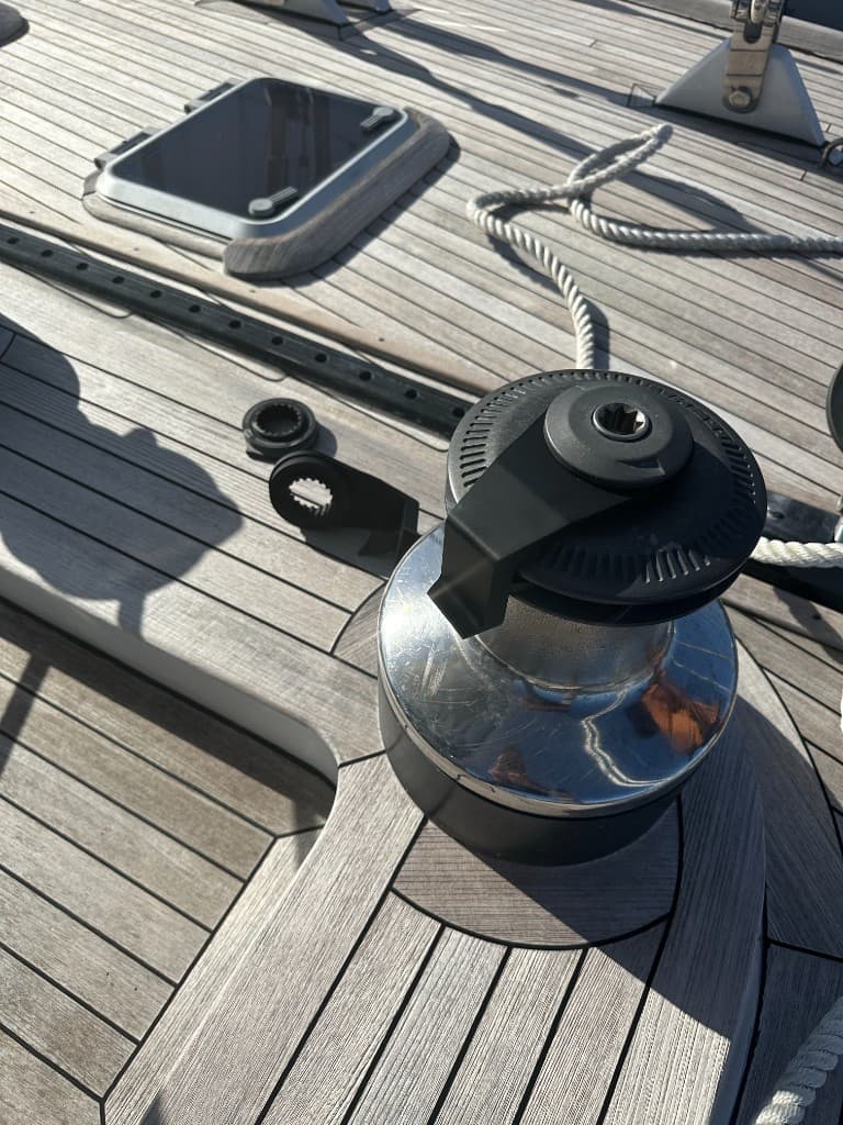 White engineered polymer windlass rope stop beside a fractured metal original on teak decking